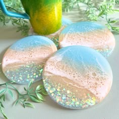 three blue and white soap covered rocks next to a green cup with sprinkles