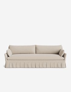 a beige couch with pleated cushions on it's back and arms, against a white background