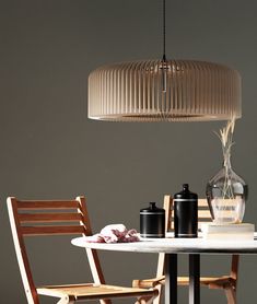 a table with two chairs and a vase on it next to a lamp hanging from the ceiling