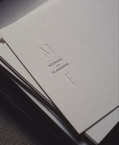 two white business cards with the letter m on them are stacked next to each other