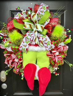 a christmas wreath with green stockings and red shoes hanging from the front door, decorated with candy canes