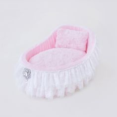 a pink and white baby bed with ruffles