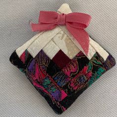 an ornament made out of fabric with a pink bow on it's neck