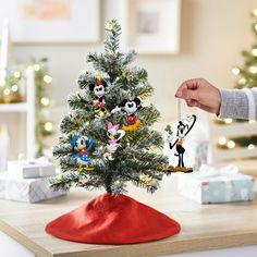 someone is decorating a small christmas tree with mickey mouse ornament ornaments on it