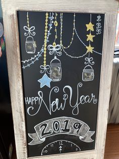 a happy new year chalkboard sign in front of a refrigerator with magnets on it