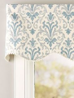 a window with a blue and white damask valance hanging from it's side