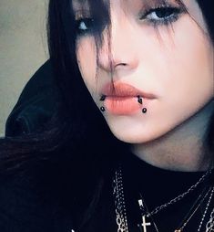 a woman with black hair and piercings on her nose