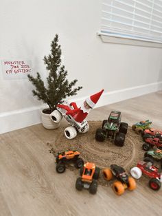 there are many toy trucks and cars in the sand pit next to a christmas tree