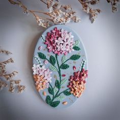 a painted oval with flowers on it next to some dried flowers and branches in the background