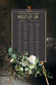 a wedding seating chart with flowers and greenery on an easel in front of a wall