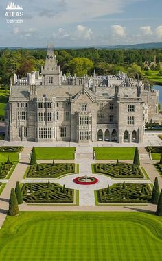 an aerial view of a large castle like building with hedges in the foreground and trees surrounding it