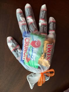 a hand that has some kind of candy wrapped in plastic on top of a table