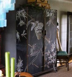 a tall black cabinet with white flowers painted on it's doors and drawers in a living room