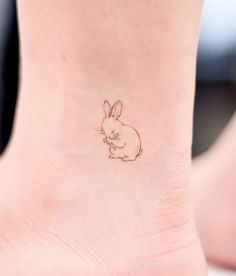 a small tattoo on the ankle of a woman's foot with a rabbit sitting in it