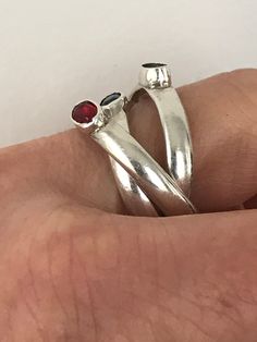 This fun rolling ring is made up of three interlocking sterling silver bands, each bezel set with a green, red or blue glass stones. Each band is marked 925 and is about 3mm wide. This ring is about a size 8 1/2 and is in very good preloved condition. Please see all photos for details, as well as, condition. Thank you for looking! Adjustable Red Sterling Silver Stackable Rings, Red Stackable Open Ring, Red Gemstone Sterling Silver Stackable Rings, Silver Three-stone Ruby Ring Gift, Silver Three Stone Ruby Ring As Gift, Filigree Diamond Ring, Rolling Ring, Silver Bands, Poison Ring