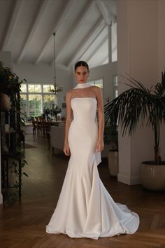 a woman in a white dress standing on a wooden floor