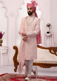 a man in a pink outfit standing on a rug with his hand on his hip