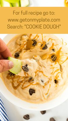 a hand holding an apple slice over a bowl of oatmeal cookie dough