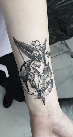 a black and white photo of a flower tattoo on the left arm, with an arrow in the middle