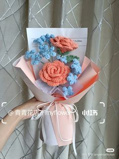 a hand holding a bouquet of crocheted flowers on top of a white envelope