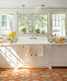 the sun shines through the windows in this white kitchen with an area rug on the floor