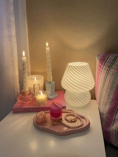 two candles are sitting on a tray next to some other items that include rings and bracelets