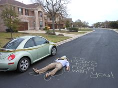 a person laying on the ground next to a car