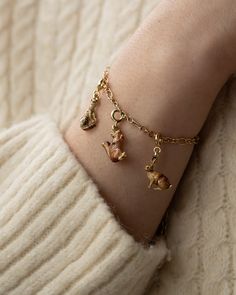 a woman wearing a gold bracelet with charms