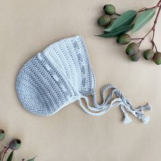 a crocheted hat laying on top of a table next to an olive branch