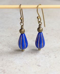 "small boho dangle earrings cobalt blue glass teardrop earrings These light and dark blue beads remind me of faded blue jeans. They are small, Czech glass ribbed teardrops accented with metallic gold/brass colored recessed ribs. A small antiqued brass bead sits on top. Hook ear wires are antiqued brass. Length of earrings from top of ear wires is 1 3/8\". Glass teardrops measure 13mm ling, 1/2\". You can enter my shop here: gypsydangles.etsy.com" Nickel Free Blue Teardrop Earrings, Nickel Free Blue Teardrop Pendant Earrings, Blue Teardrop Drop Earrings, Adjustable Hypoallergenic Blue Teardrop Earrings, Blue Adjustable Hypoallergenic Teardrop Earrings, Blue Long Drop Teardrop Earrings With Ear Wire, Blue Hypoallergenic Adjustable Teardrop Earrings, Blue Teardrop Earrings With Dangling Beads, Blue Teardrop Earrings With Ear Wire