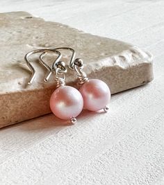 Swarovski Crystal Pearls in ethereal Blush Pink are wrapped in shiny sterling silver and suspended from hook style ear wires. Lightweight and perfect for the most lovely bridesmaids gifts or daily wear to add a touch of color to your office attire. * Pearl: Swarovski 8mm in Blush Pink, as shown More colors available! * Metal: .925 Sterling silver * Length: About 1 inch from top of the ear wire Brides needing multiples for your besties? Multiple order discounts: 3-5 pairs receive 10% off 6+ pairs Elegant Pink Earrings For Everyday Wear, Pink Elegant Everyday Earrings, Elegant Pink Everyday Earrings, Pink Everyday Jewelry With Ear Wire, Elegant Nickel-free Pink Jewelry, Minimalist Hypoallergenic Pink Jewelry, Minimalist Nickel-free Pink Jewelry, Pink Minimalist Earrings As Gift, Pink Pearl Earrings For Wedding