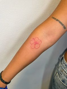 a woman's arm with a small pink flower tattoo on the left inner arm