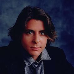 a man wearing a suit and tie in front of a blue background with his eyes wide open