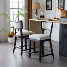 two stools in front of a desk with a potted plant next to it