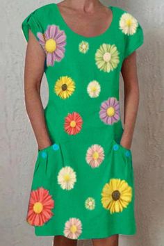 a woman standing in front of a wall wearing a green dress with flowers on it