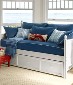 a day bed with blue and white pillows in a living room next to a window