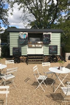 a small food truck with tables and chairs around it in the middle of a gravel area