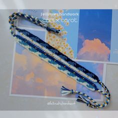 a blue, white and black beaded lanyard with tassels on it