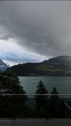 the sky is very dark and cloudy with mountains in the background