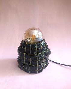 a black and yellow lamp with a glass ball on it's top sitting on a white surface