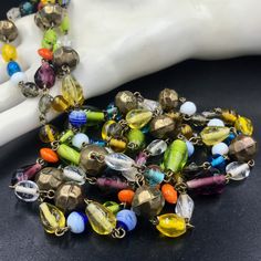 "This is one of my favorite types of necklaces to find. It's a LONG flapper style - over the head with no fastener/clasp - necklace made from SMALL wired art glass beads. The multi-colored beads are lovely with some being more \"solid\" in terms of color and others being more \"clear\" or \"transparent.\" The different shaped beads are wired together. There are 12 orb shaped brass beads evenly interspersed among the glass beads. I think the necklace is most likely a 1970s reproduction rather than a true 1920s/1930s flapper era necklace. For this reason, I was hesitant to date it but know it to be vintage by Etsy's standards. The beads could be Czech glass or even made in Japan. The necklace can be worn long or doubled. It has a HANG length of 29 inches. The width of the necklace varies wit Vintage Adjustable Multicolor Necklaces, Vintage Multicolor Glass Necklaces, Vintage Adjustable Necklaces With Colorful Beads, Vintage Multicolor Spacer Beads, Multicolor Glass Costume Jewelry Necklaces, Retro Multicolor Necklaces For Jewelry Making, Multicolor Glass Costume Jewelry Necklace, Vintage Glass Jewelry For Festivals, Retro Multicolor Adjustable Necklaces