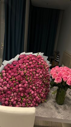 pink roses in vases sitting on a table next to a white chair and mirror