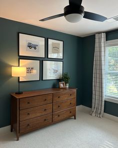 a living room with blue walls and pictures on the wall, along with a dresser