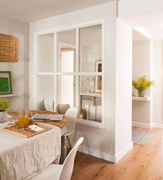 the dining room table is set for two with white linens and place settings on it