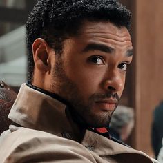 a close up of a person wearing a trench coat and looking at the camera with an intense look on his face