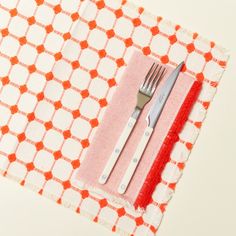 a fork and knife are sitting on top of a placemat with an orange border