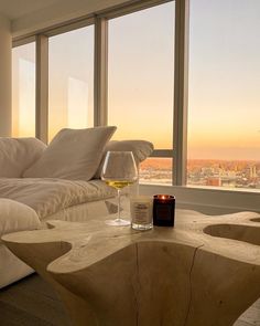 a glass of wine sitting on top of a table in front of a large window