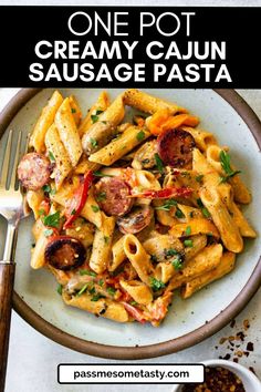 one pot creamy cajun sausage pasta in a white bowl with a fork on the side