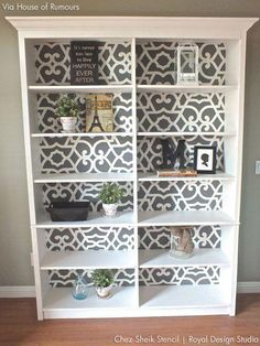 a white bookcase with decorative stencils on it