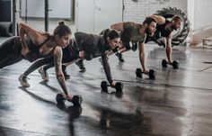 group of people doing push ups with dumbbells